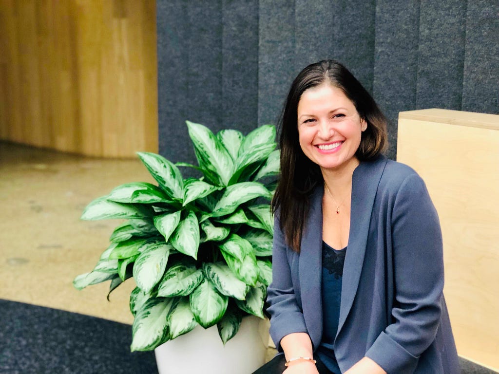 Young woman smiling next to a plant