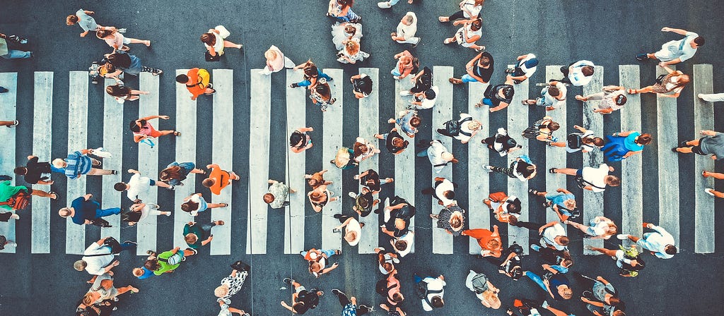 Busy city crosswalk view from above, representing the vulnerabilities large cities face as centralized systems in a pandemic.