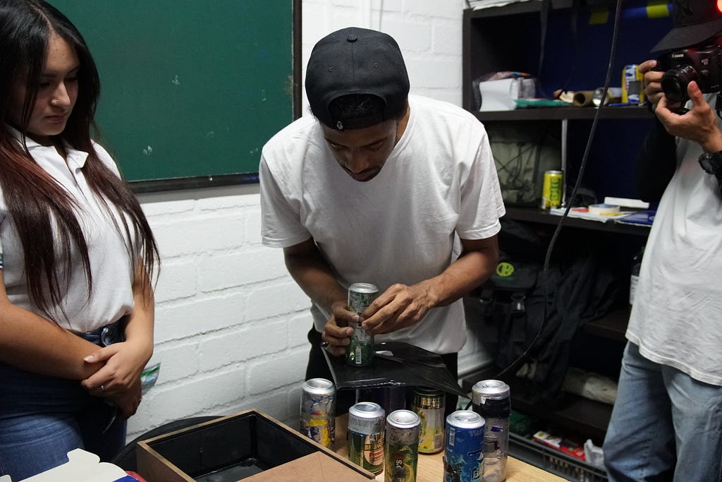 A photography instructor show two students how to make pinhole cameras.