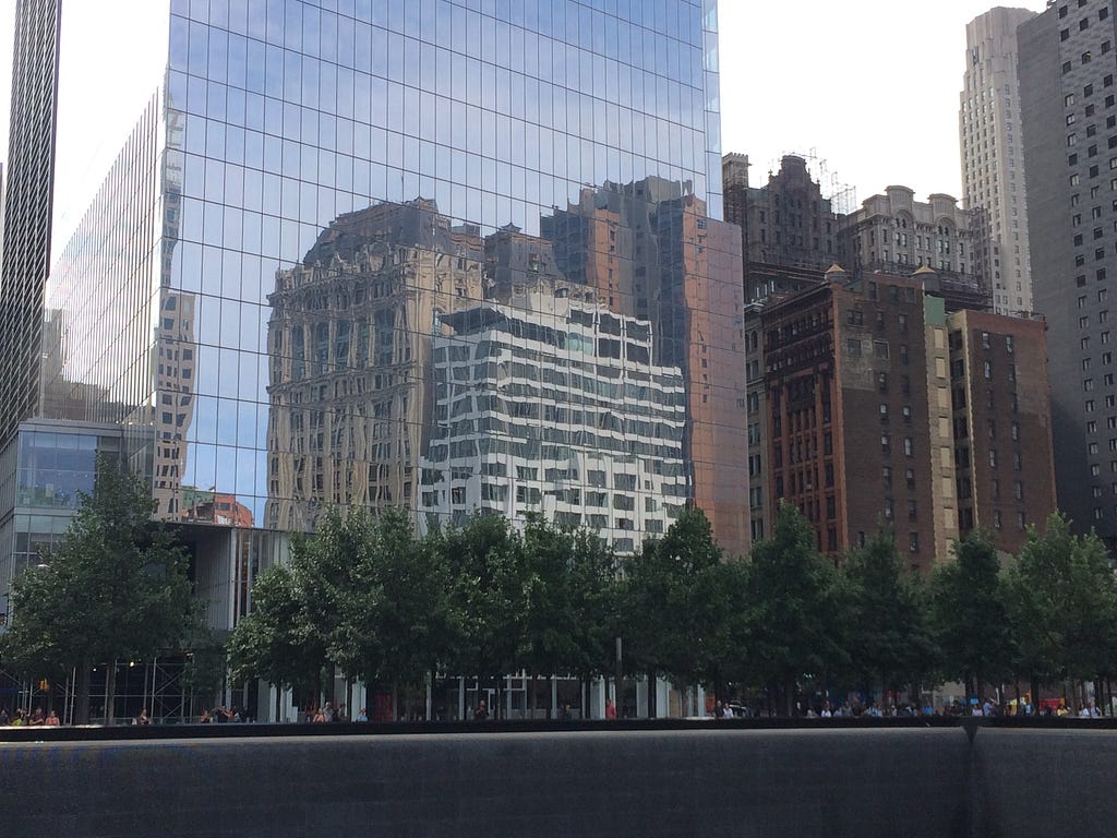 A photo of a reflection of older buildings. The reflection is in a newer all glass window building.