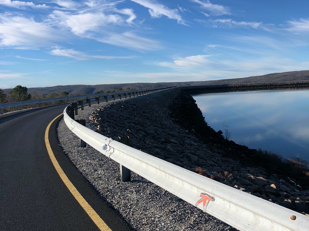 Road by a reflective lake, blue sky