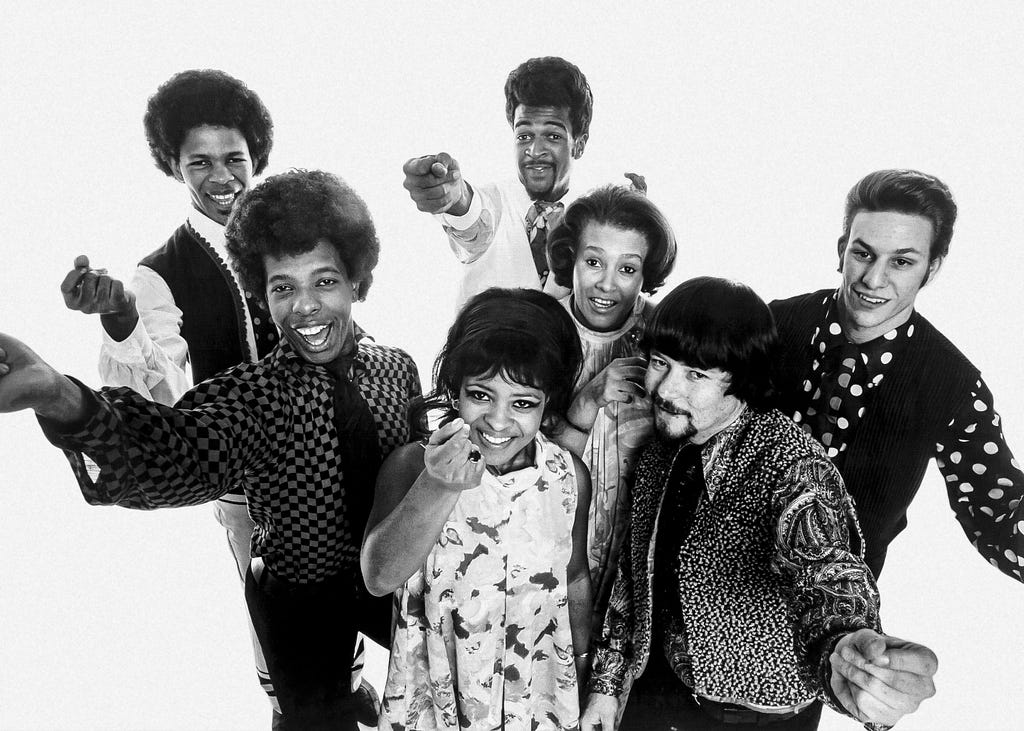 Publicity photo of the American band Sly and the Family Stone in 1968. From left to right: Freddie Stone, Sly Stone, Rose Stone, Larry Graham, Cynthia Robinson, Jerry Martini, Greg Errico. Distributed by Epic Records, Daedalus Management, and William Morris Agency, Inc. Photographer uncredited and unknown.