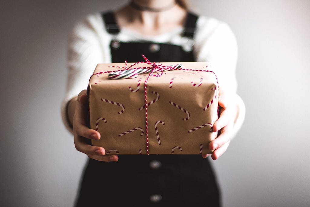 Women holding a gift-wrapped package in her hands.