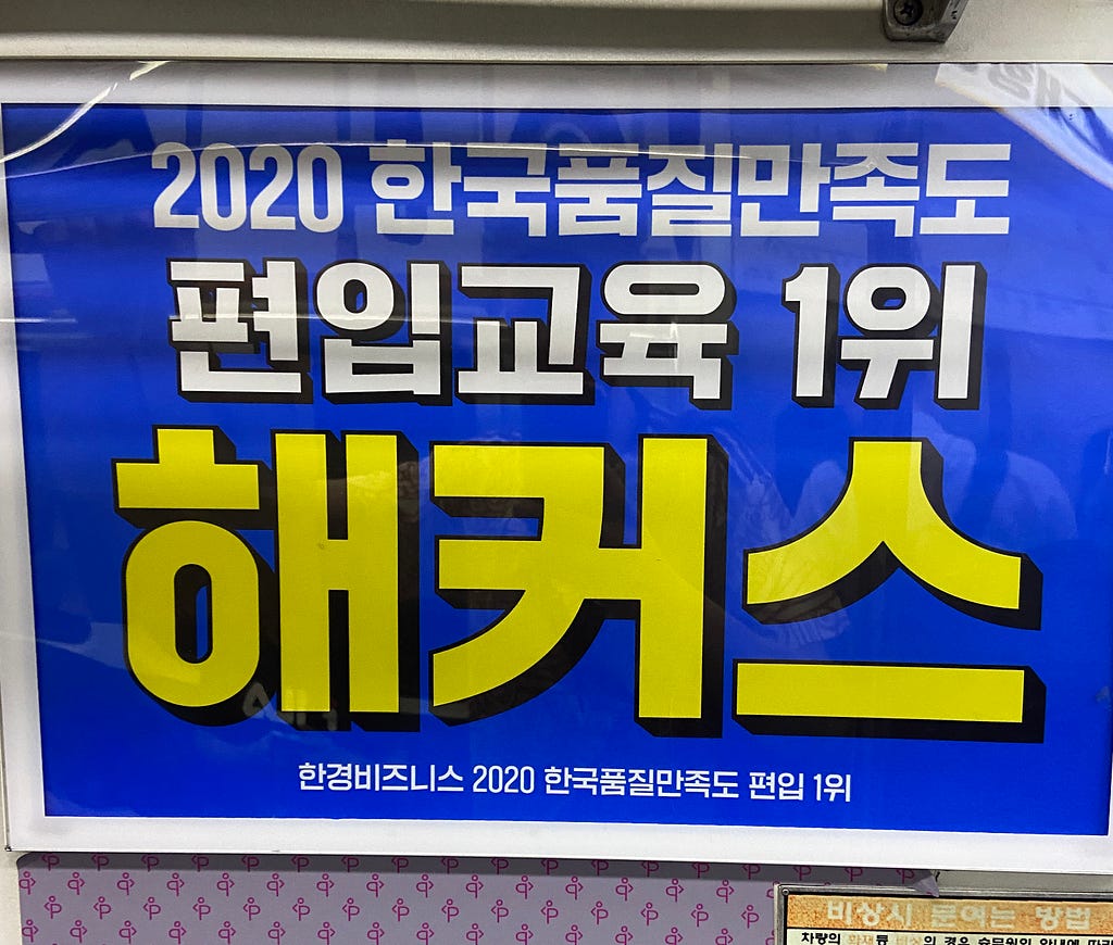 Anúncio de fundo azul, con inscrições coreanas em branco e amarelo. Não há nenhum ícone ou ilustração, apenas texto.
