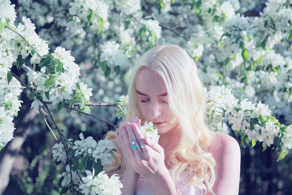 An 18 year old young woman enjoying the lovely spring blossoms. The flowers were highly scented, like a bottle of perfume. She graduates from high school in a few weeks and she wanted her senior pictures taken at this botanical garden that is nearby.