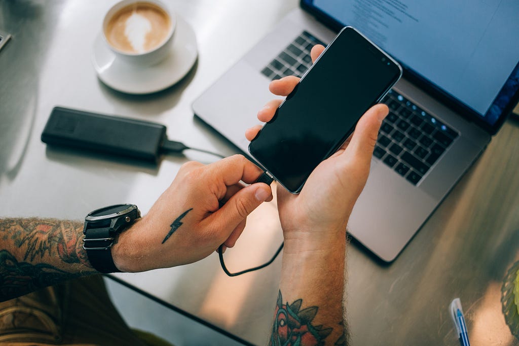 Urban man plugs phone into external power bank