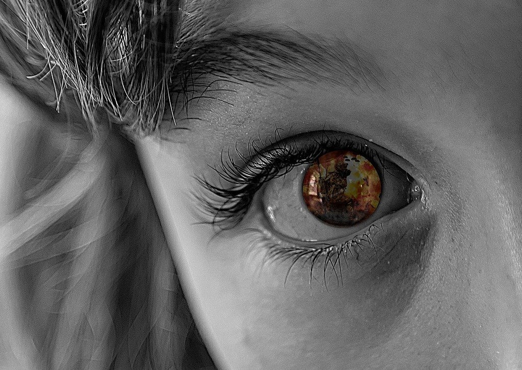 A child’s eye reflecting a images of fire