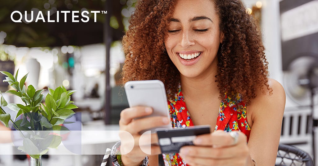 Woman sitting outside looking at her mobile phone holiding a credit card