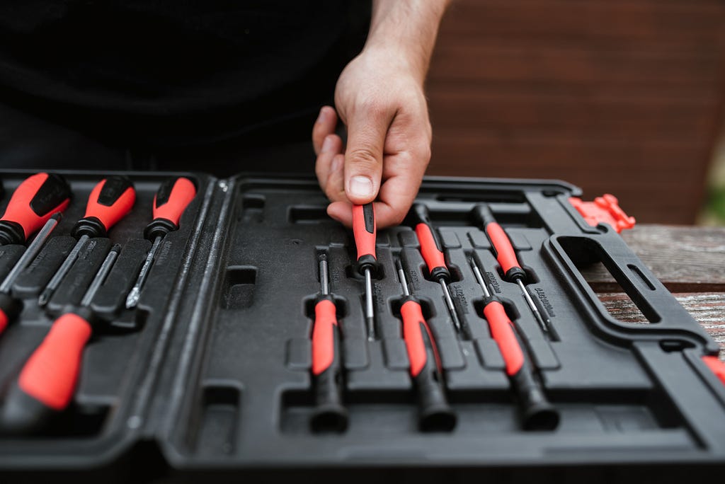 A faceless master choosing a screwdriver from the toolbox.