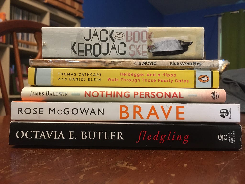 A stack of the six books read during March 2023, as listed in the article, set on top of a dining room table.