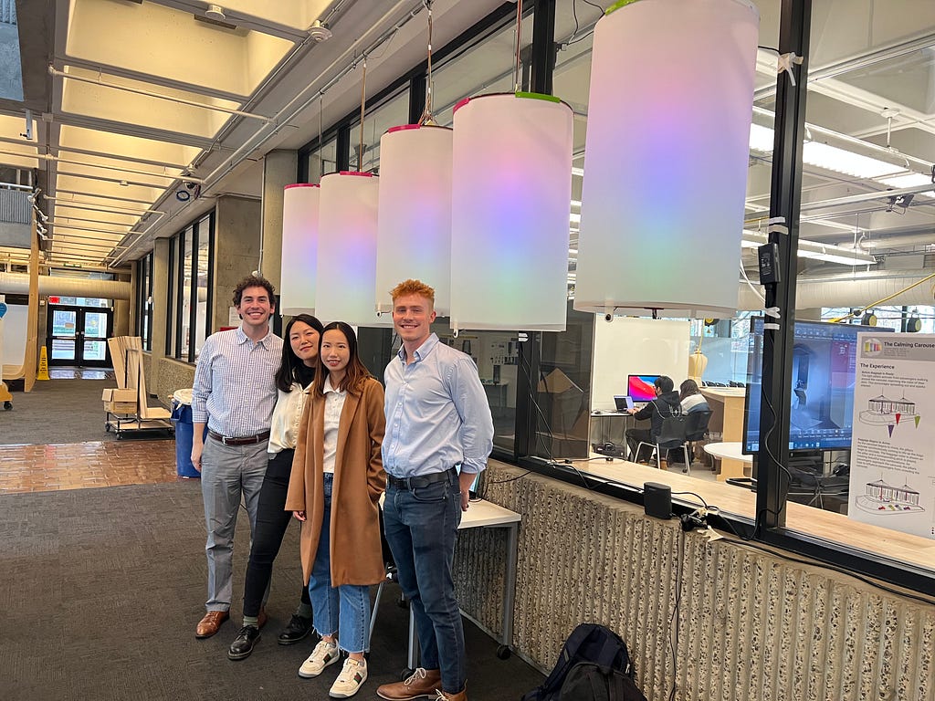 Four students in front of an interactive light exhibit