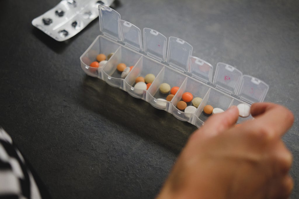 Woman sorting medication into daily meds container.