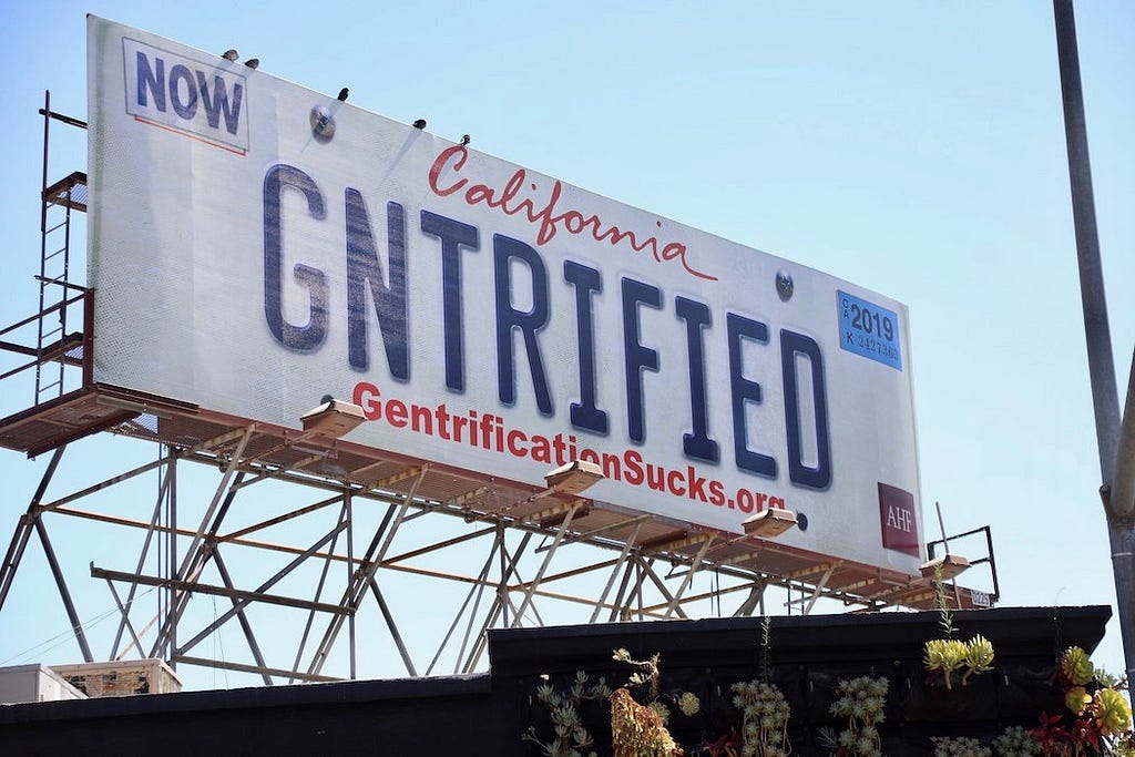 Billboard designed like a California license plate with letters GNTRIFIED