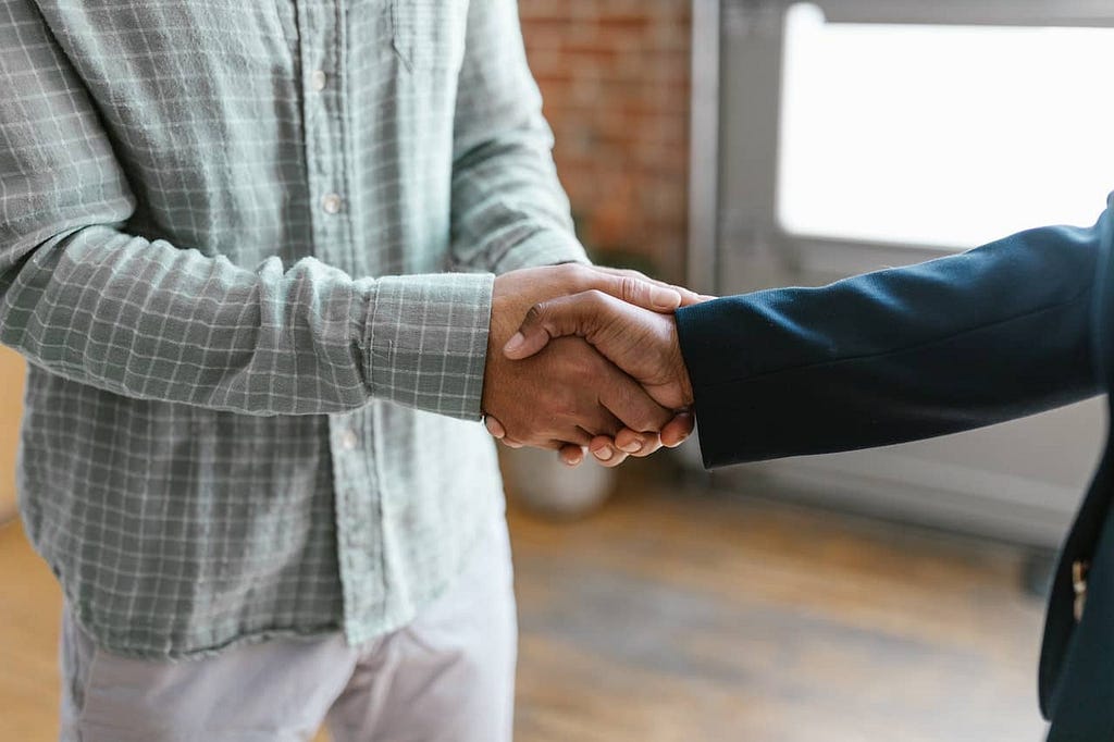 two hands embrace in a handshake after networking to benefit their client attraction strategy