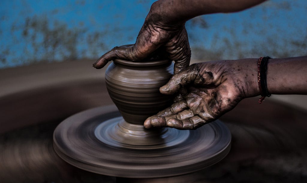 A potter turns a vase on a potting wheel.