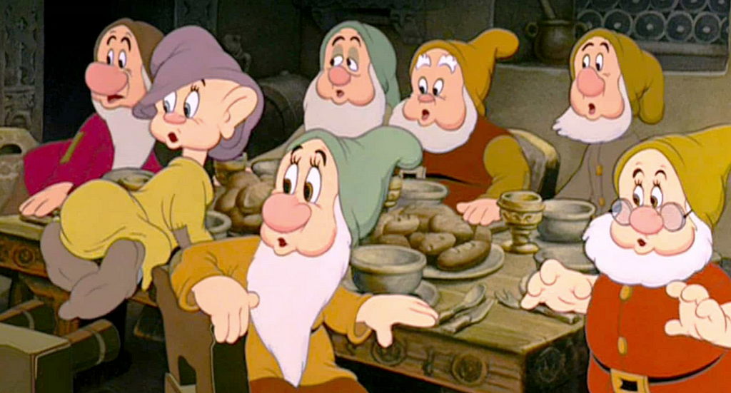 The seven dwarfs looking surprised at the dinner table.