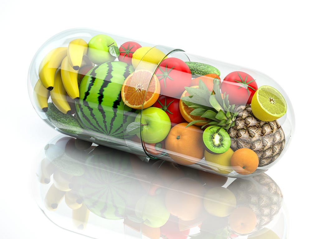 Vitamin pill capsule with fruits and vegetables indicating that food is medicine and health eating concept.
