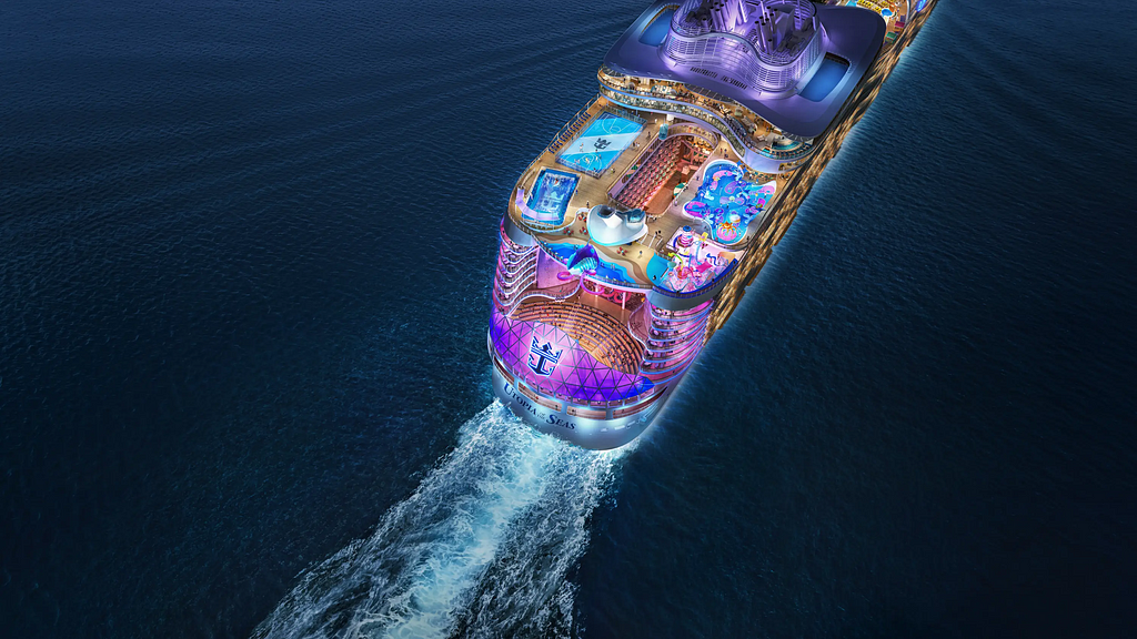 Image shows aerial view of Utopia of the Seas cruise ship from Royal Caribbean sailing across the ocean at night