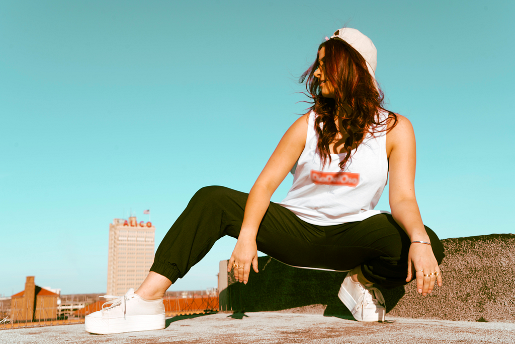 Model wearing The Dia gang Tank Top in front of the Alico building in Waco, Tx