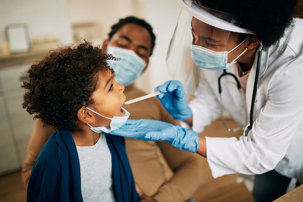 doctora examinando a un niño y padre detras