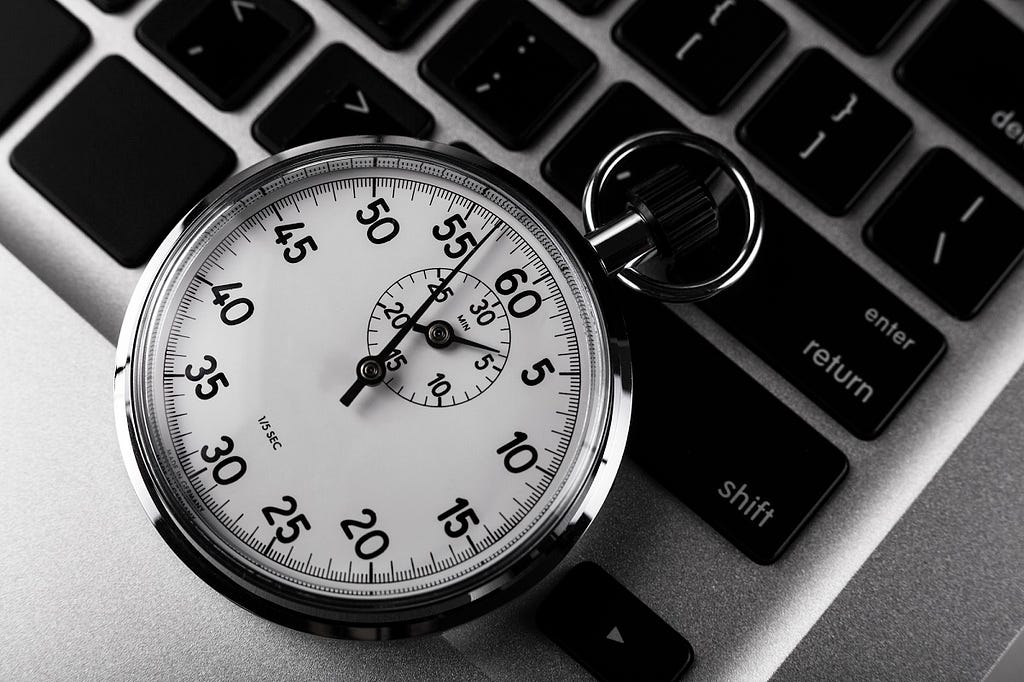 A stopwatch sitting on top of a laptop keyboard.