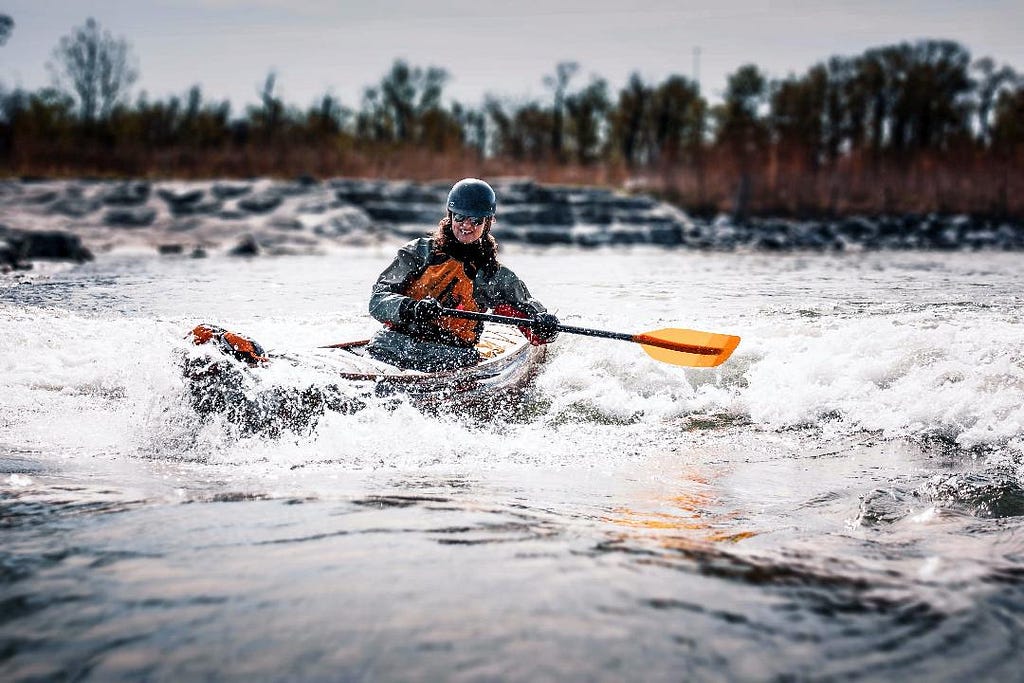 Solo canoeist surfing on a wave.