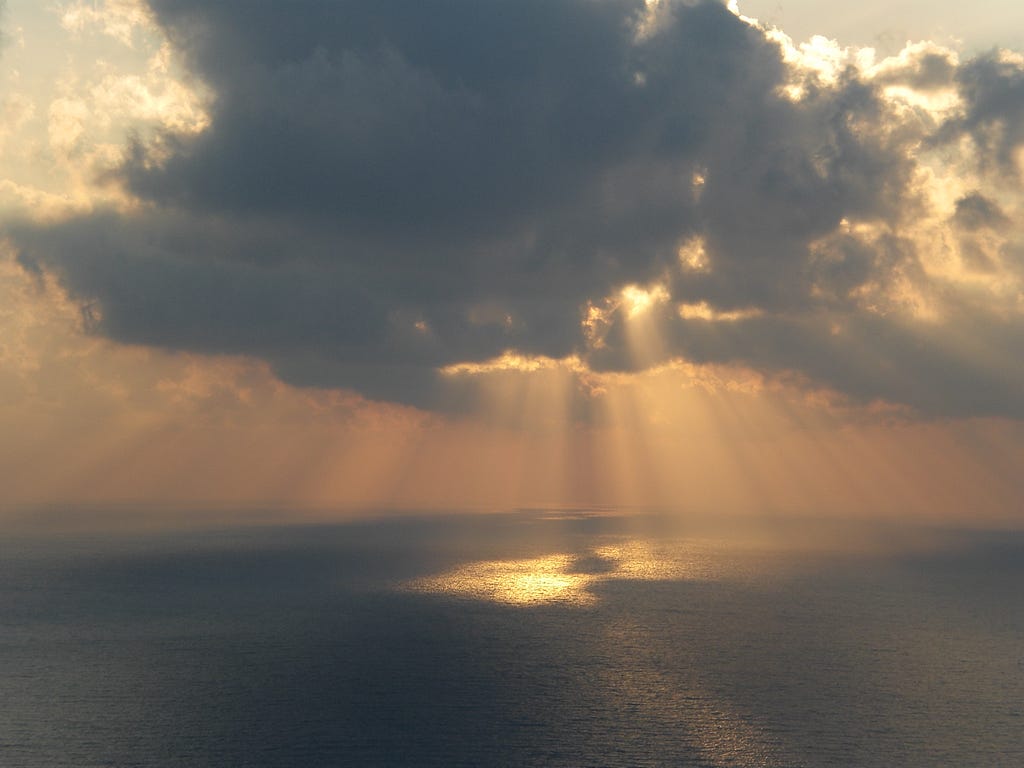 Light piercing through the clouds and down at the ocean. A divine moment in time.