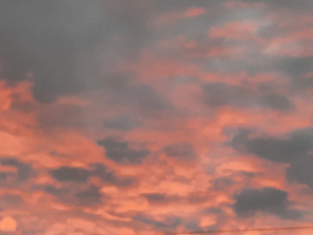 The sky and clouds in a reddish hue during a sunset.