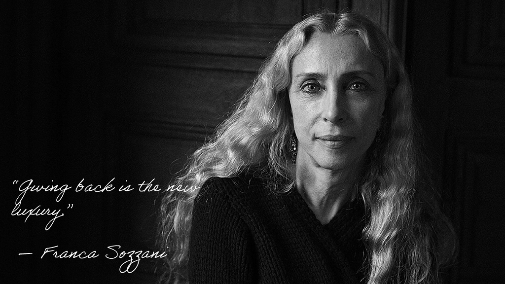 A black-and-white photograph of Franca Sozzani, with white script: “Giving back is the new luxury. —  Franca Sozzani”