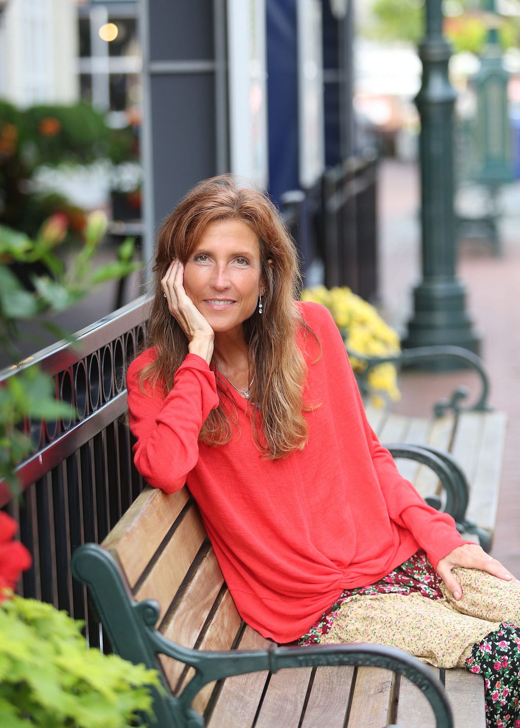 Award winning children’s book author, Raven Howell, sitting on a bench in a pink blouse.