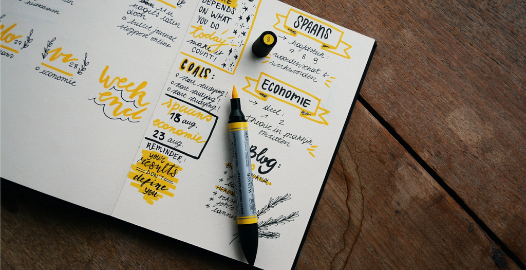 A weekly journal, someone’s writing in it with yellow marker, it has neatly organized categories like a good bullet journal would