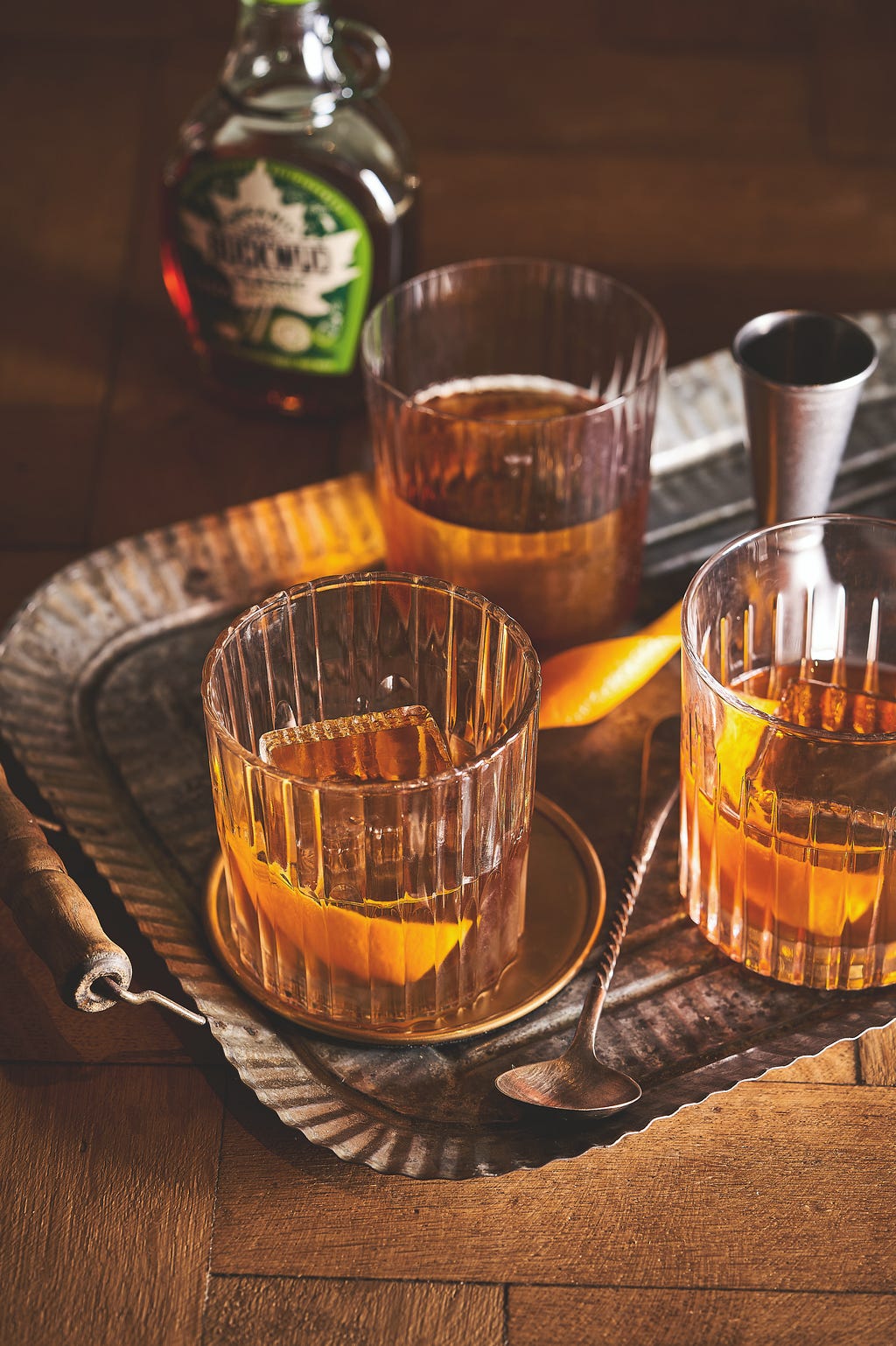 three cocktail glasses with maple syrup old fashioneds sitting on a tray