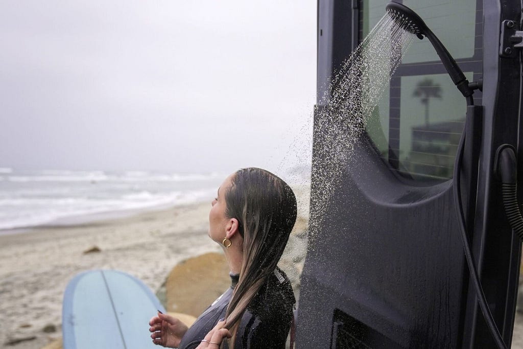 Woman taking a shower outside a campervan