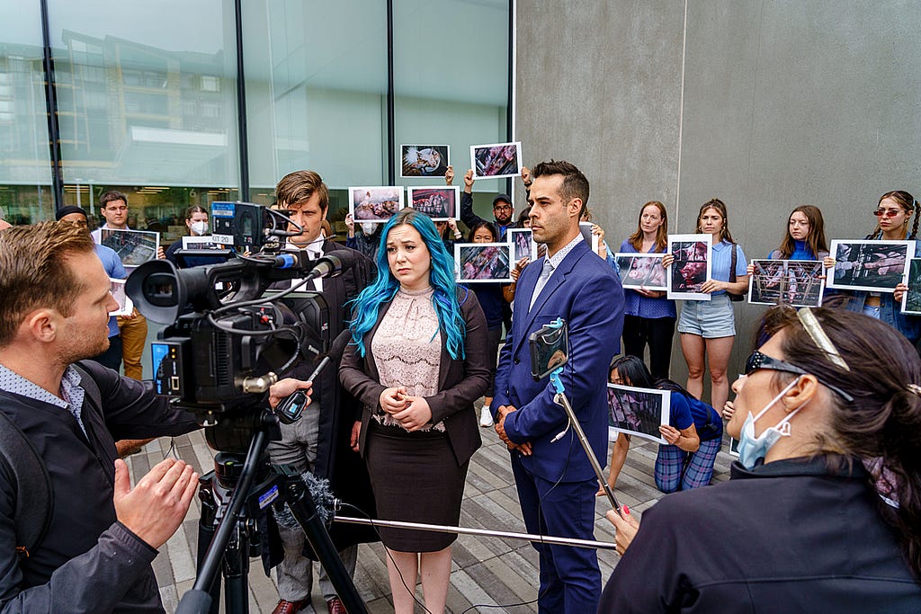 Defence lawyer Leo Salloum and animal advocates Amy Soranno and Nick Schafer speak to CTV News and other media outside the Abbotsford, law courts after Amy and Nick’s sentencing hearing. Images of pigs living on the farm in 2019 are displayed by animal advocates in the background.