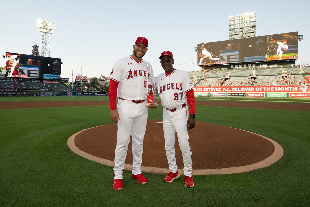 Estévez and Manager Ron Washington smile for a photo as Estévez holds his Reliever of the Month award during his pregame ceremony.
