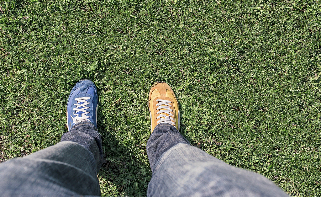 Two identical shoes, one is blue, the other is yellow.