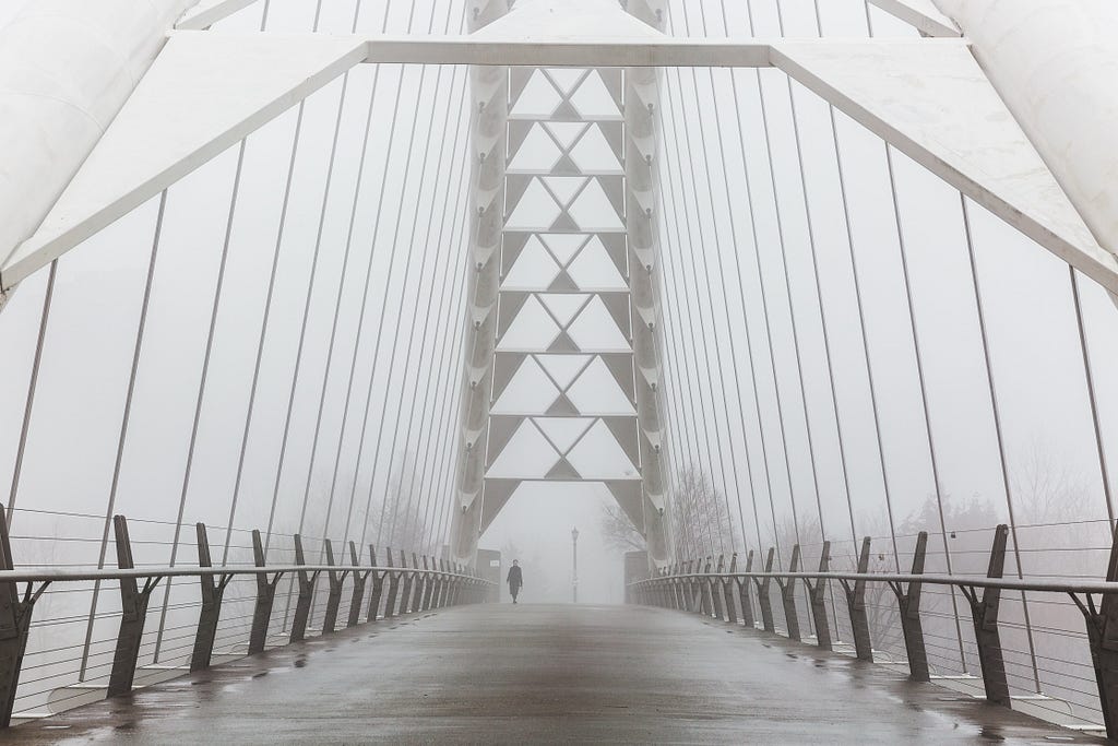 a person walking across a bridge in fog