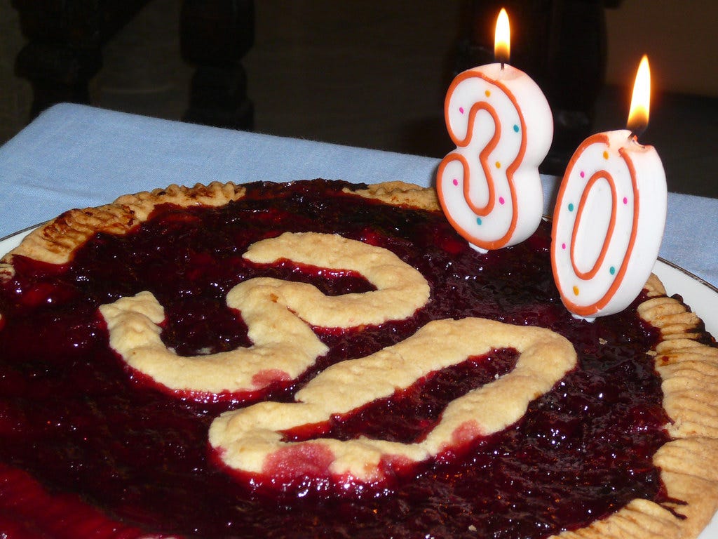 A pie that says 30 on it, and has candles that also show the number 30.