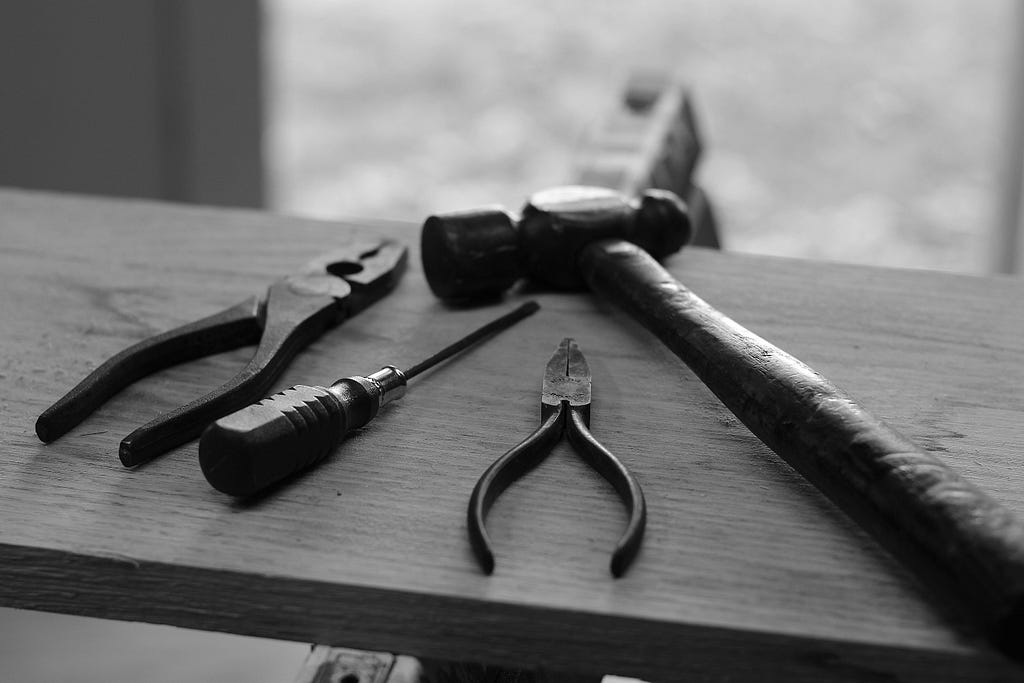 A black and white photo of 4 handheld tools laying on a table