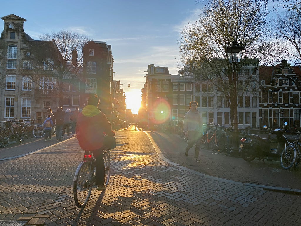 A bicycle crosses a bridge at sunset in the canal city of Amsterdam.
