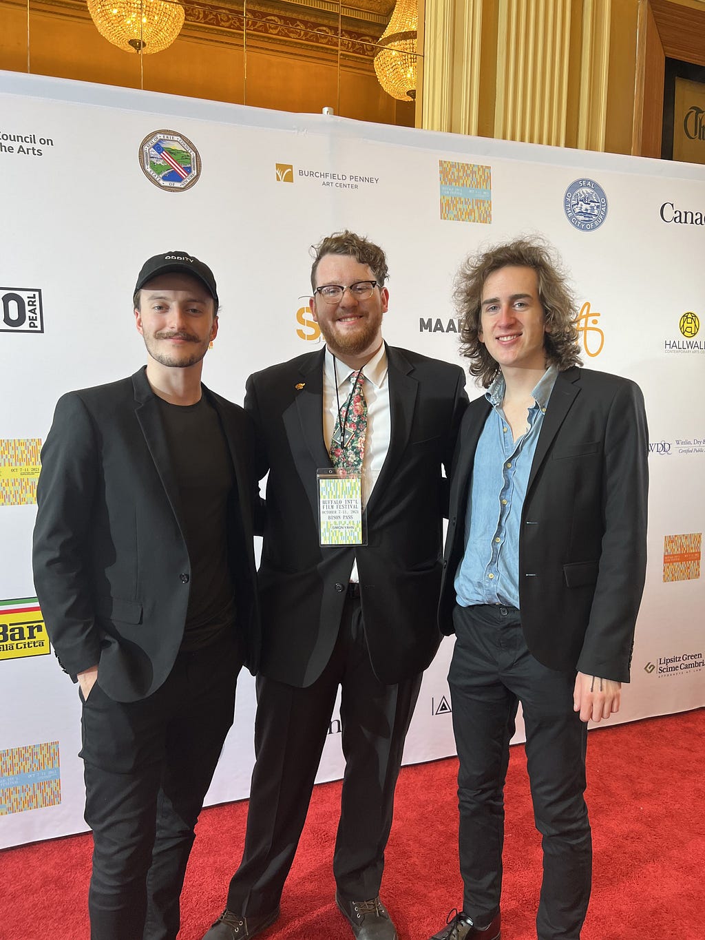 Liam O’Brien, Simon Yahn, and Danny Pakulski standing on a red carpet in front of a logo backdrop at the Buffalo International Film Festival