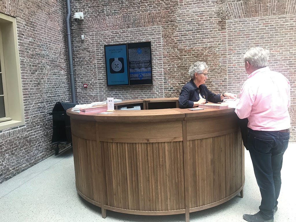 On-screen advertising behind the multimedia counter of Museum De Lakenhal in Leiden. Volunteers help to answer questions.