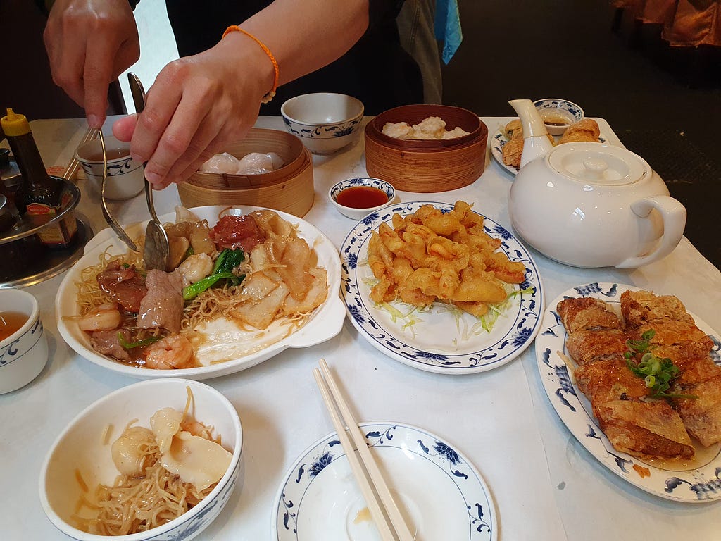 A table with Chinese food dishes and a tea pot.