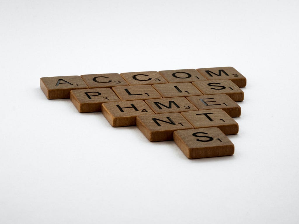 The word accomplishments written using wooden scrabble pieces.