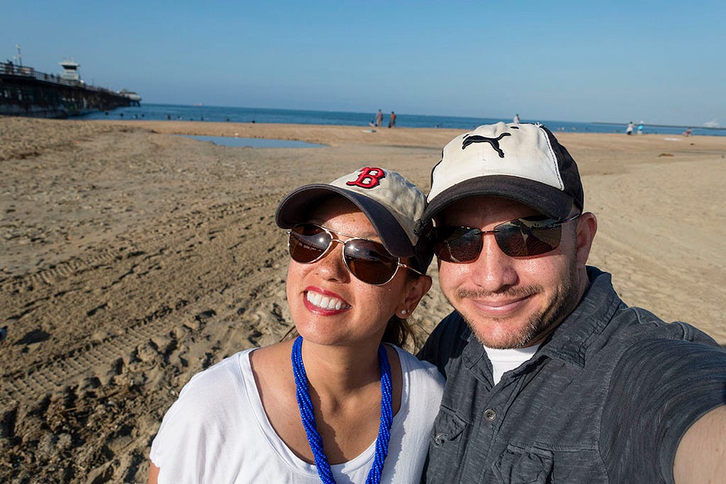 A couple on a sunny beach wearing hats and sunglasses