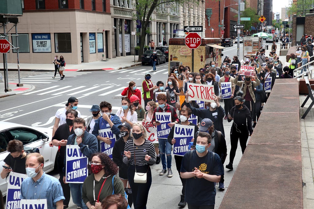 A line of protestors march from Gould Plaza towards Bobst Library