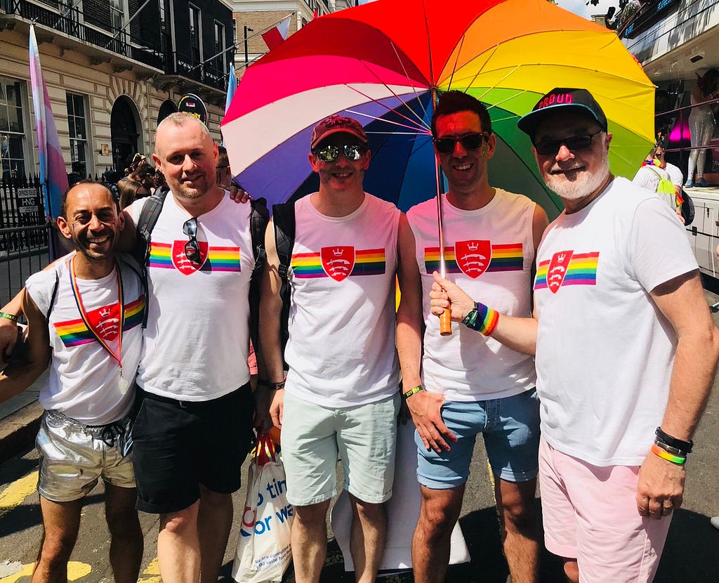Middlesex University current and former staff members with rainbow umbrella at Pride in London 2018