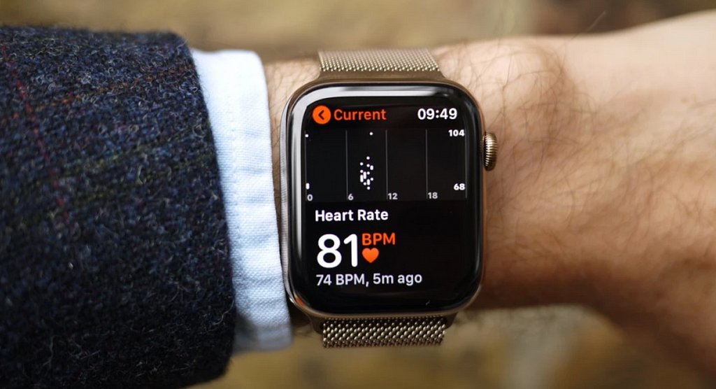 A closeup of a man’s write, featuring a smart watch displaying heart rate data