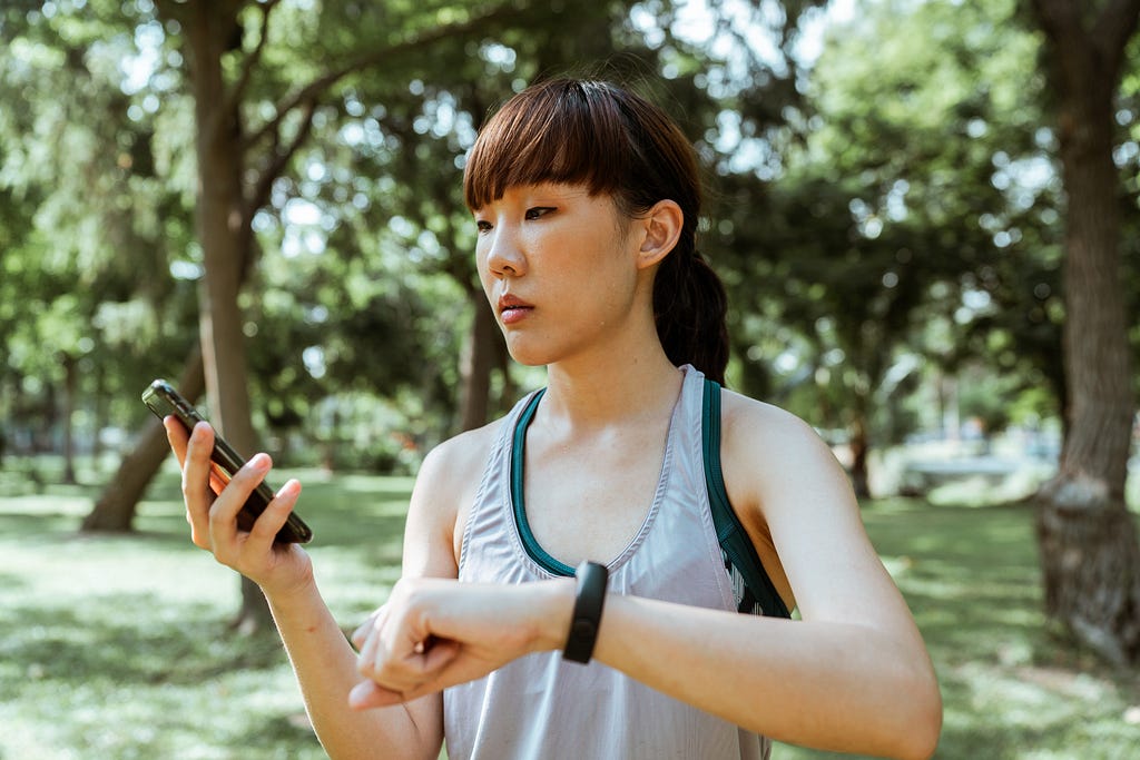 Young woman looking at a smart phone while raising her wrist with a smart watch