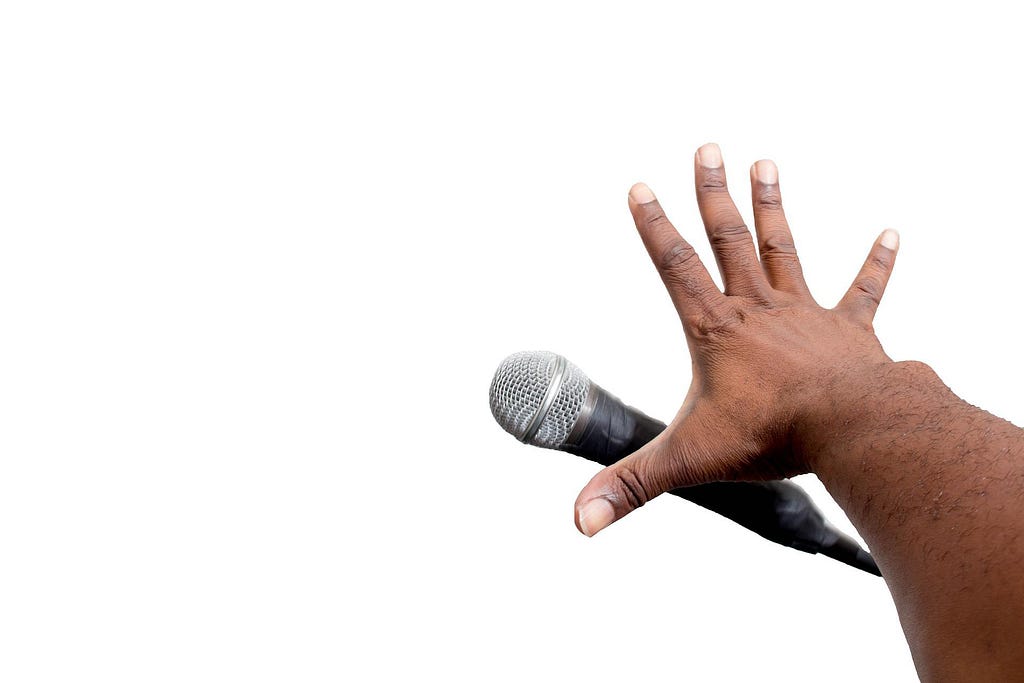 Image of an outstretched arm dropping a microphone towards the floor.